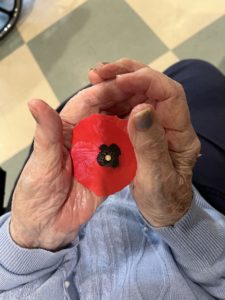 Photo of Irene Haslam holding a symbol of Remembrance, the poppy.
